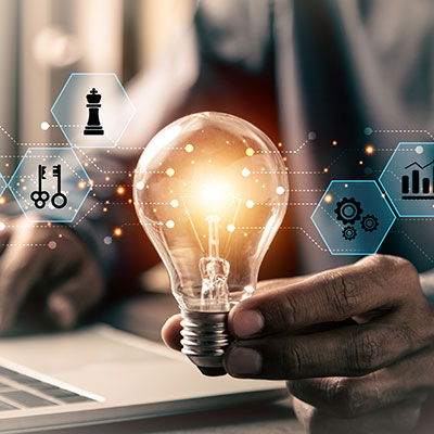 Man holding lit lightbulb while using laptop