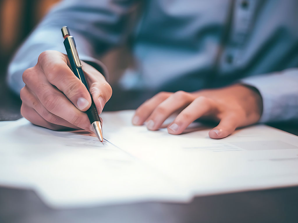Man signing paperwork with pen
